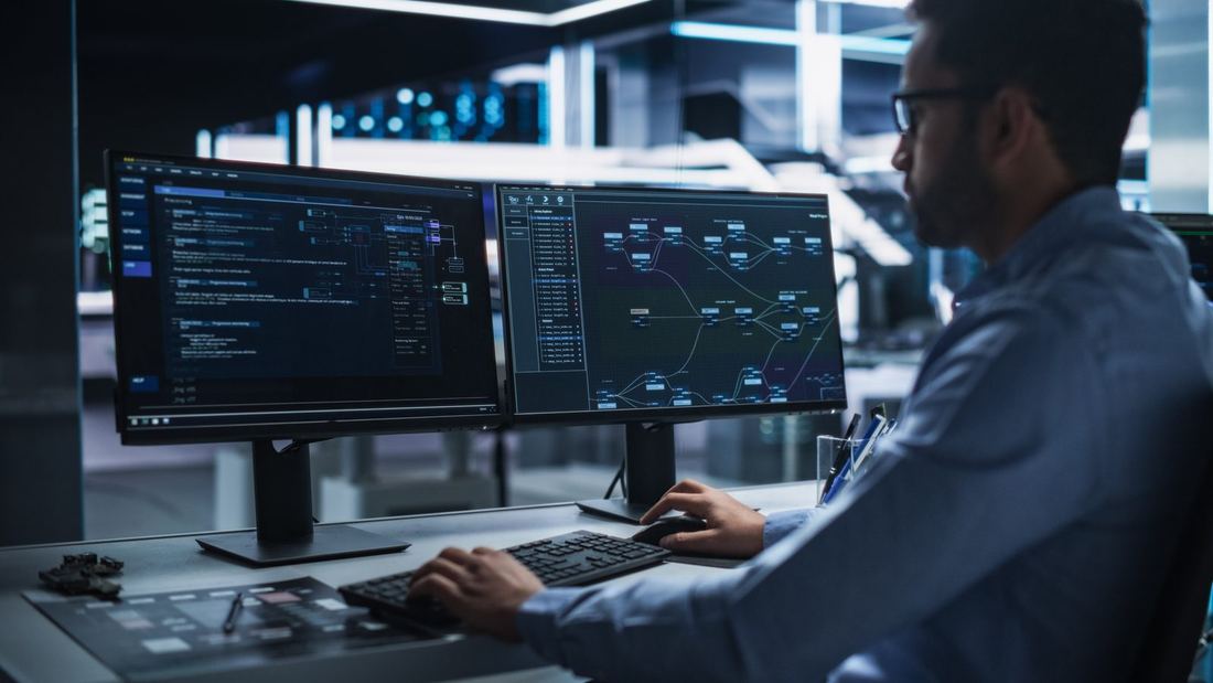 A man sitting at a computer looking at data programs.